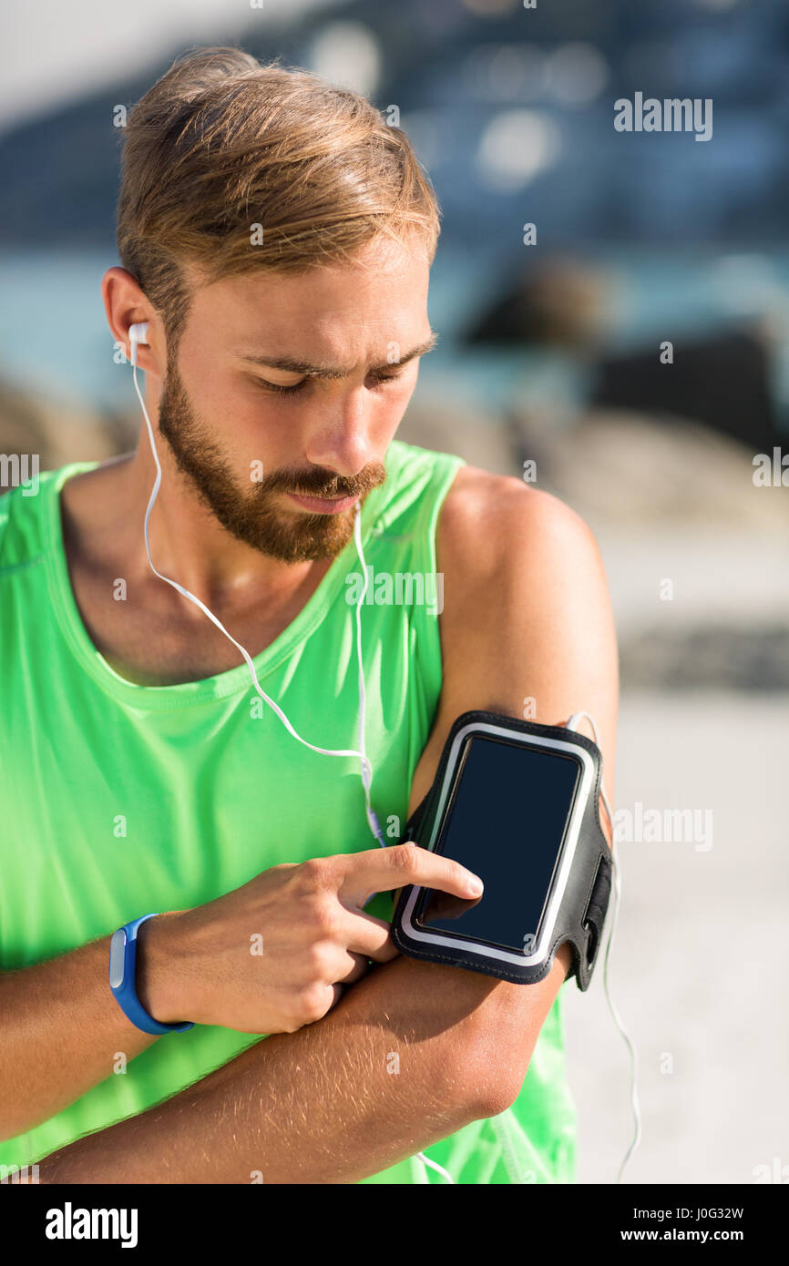 Junger Mann mit Smartphone auf Armbinde während Sie Musik hören Stockfoto