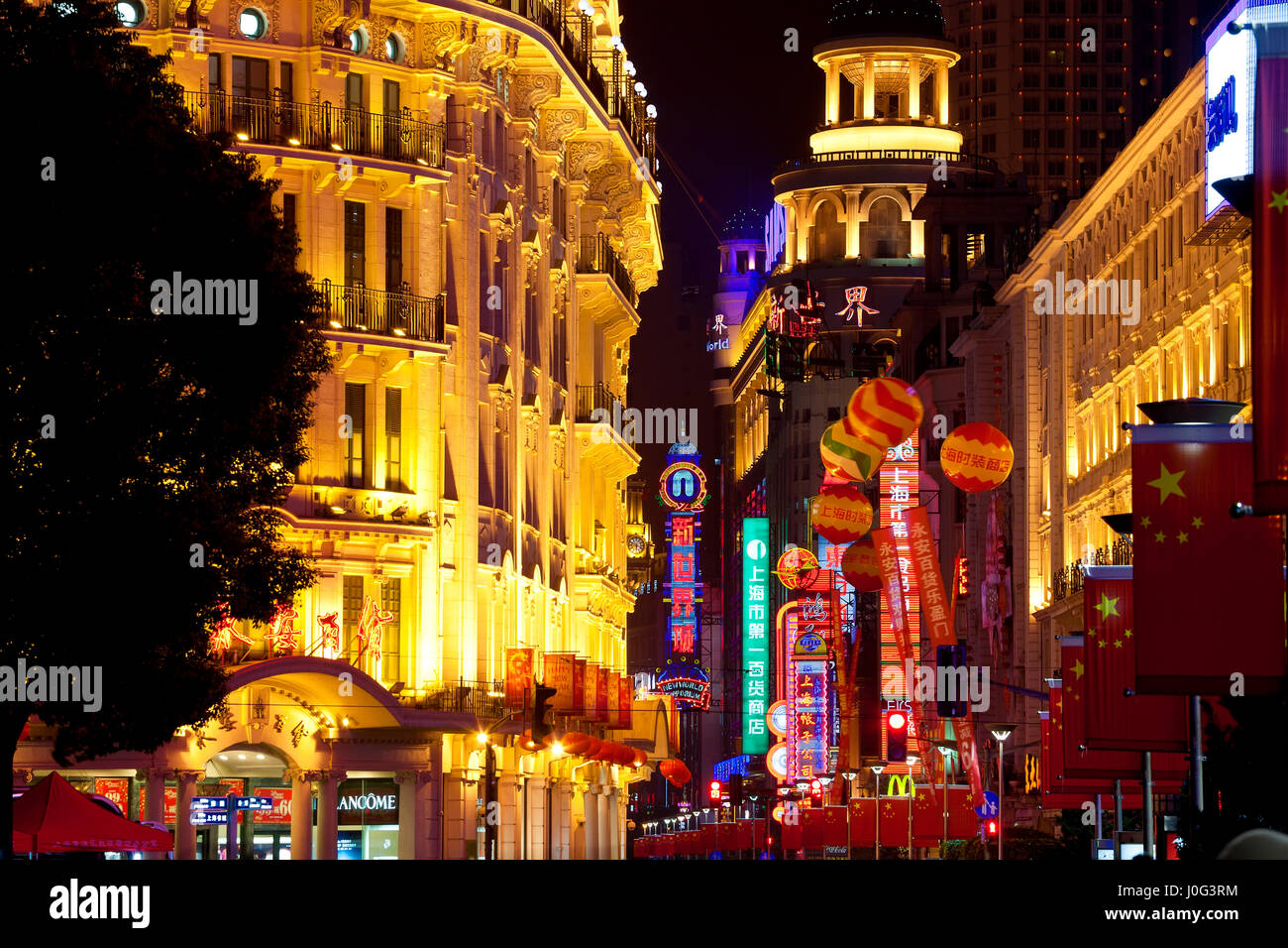 Gebäude beleuchtet in der Nacht mit chinesischen Markierungsfahnen, Nanjing Road, Shanghai, China Stockfoto