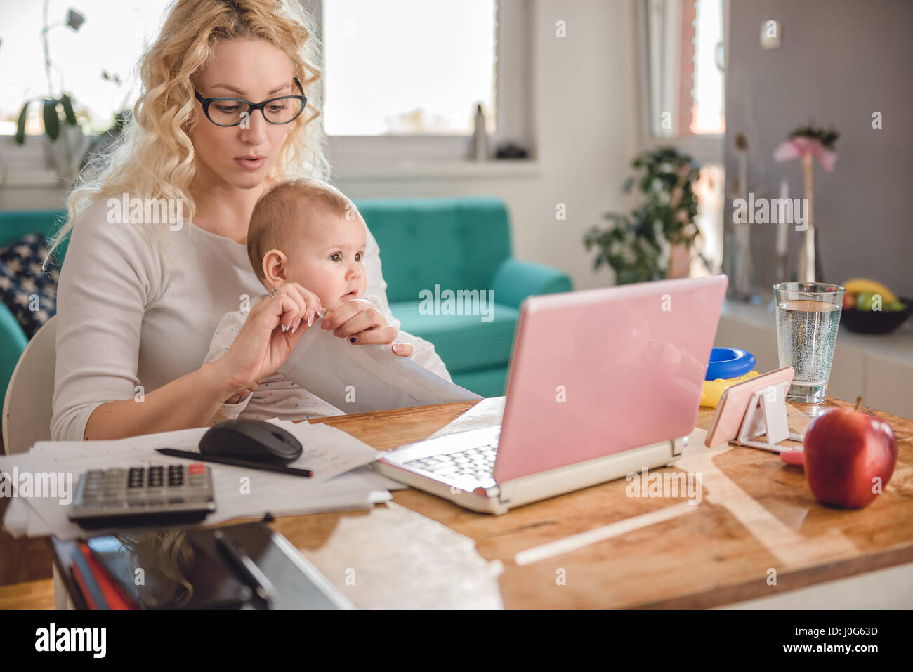 Mutter trägt Brille hält Baby und Öffnung Umschlag zu Hause im Büro Stockfoto