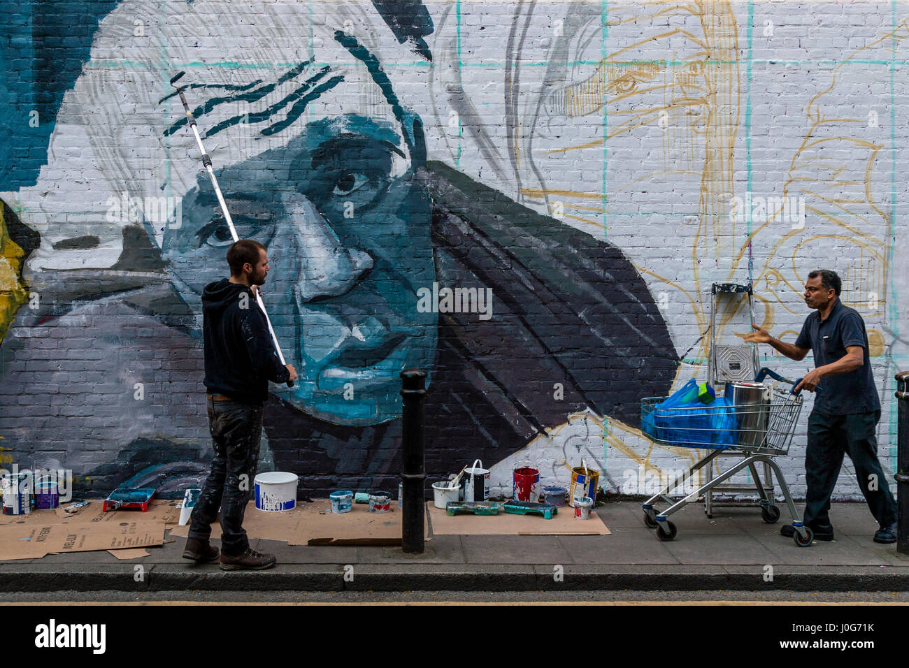 Eine Mann beschwert sich, dass er nicht, einen Graffiti-Künstler bei der Arbeit, Brick Lane, London, England passieren kann Stockfoto