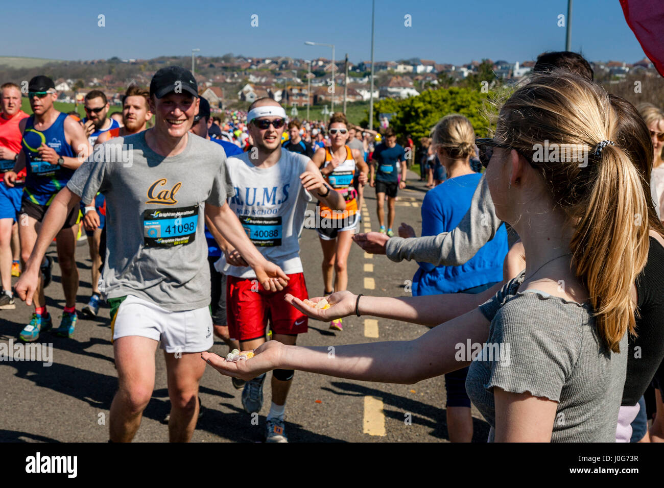 Menschen vor Ort bieten Süßigkeiten an die Athleten die Teilnahme In Brighton Marathon, Brighton, Sussex, Großbritannien Stockfoto