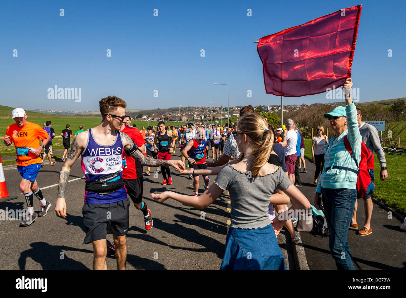 Menschen vor Ort bieten Süßigkeiten an die Athleten die Teilnahme In Brighton Marathon, Brighton, Sussex, Großbritannien Stockfoto