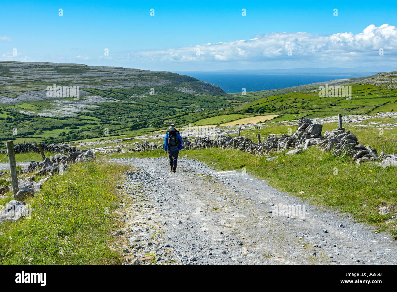 Ein Spaziergänger auf einem Track Steuerkurs nach unten in die Caher Valley, The Burren, County Clare, Irland Stockfoto