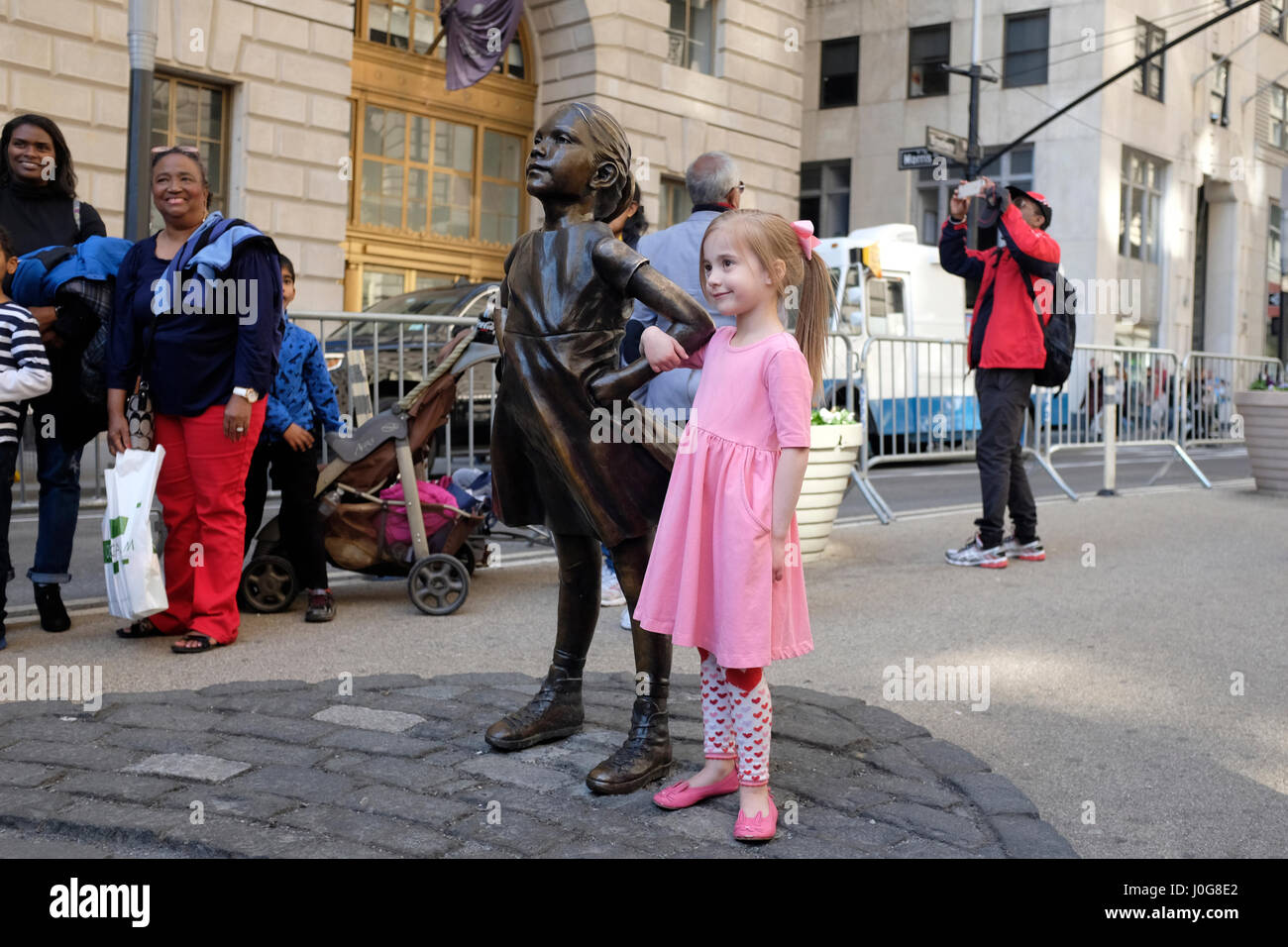 NEW YORK, NY: Ein kleines Mädchen posiert als nächstes zur 'Furchtlosen Mädchen' Statue im Finanzdistrikt von lower Manhattan.  09.04.17 Stockfoto