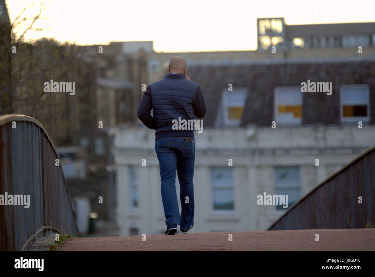 schwarzer Mann auf Handy von hinten allein zu Fuß in die Stadt Stockfoto