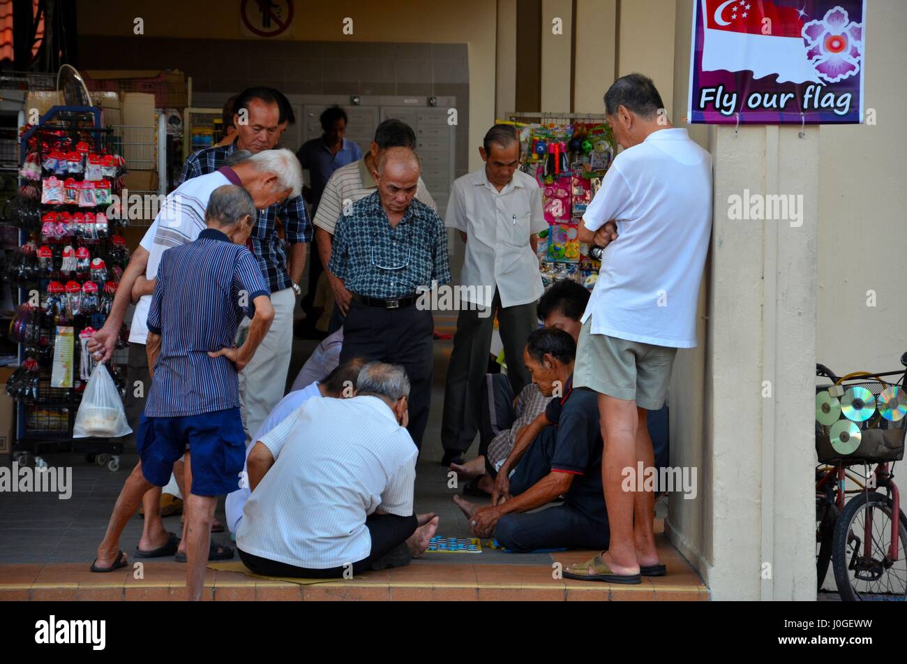 Gruppe von chinesischen Männern beobachten eine Spiel der Kontrolleure und unterhalten sich in Singapur Toa Payoh Nachbarschaft Stockfoto