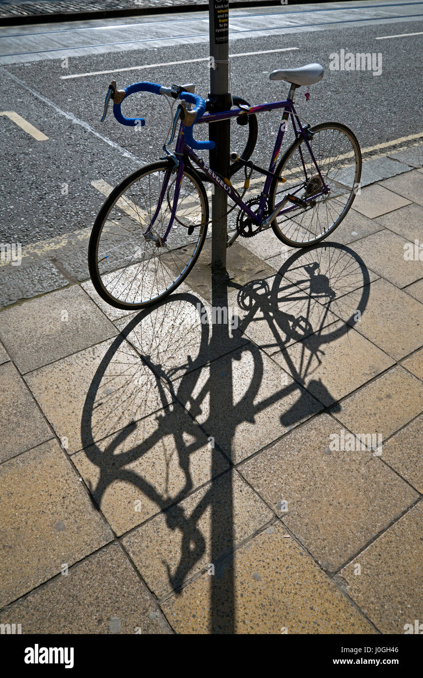 Fahrrad gesichert zu einem Beitrag wirft einen Schatten auf den Bürgersteig. Stockfoto
