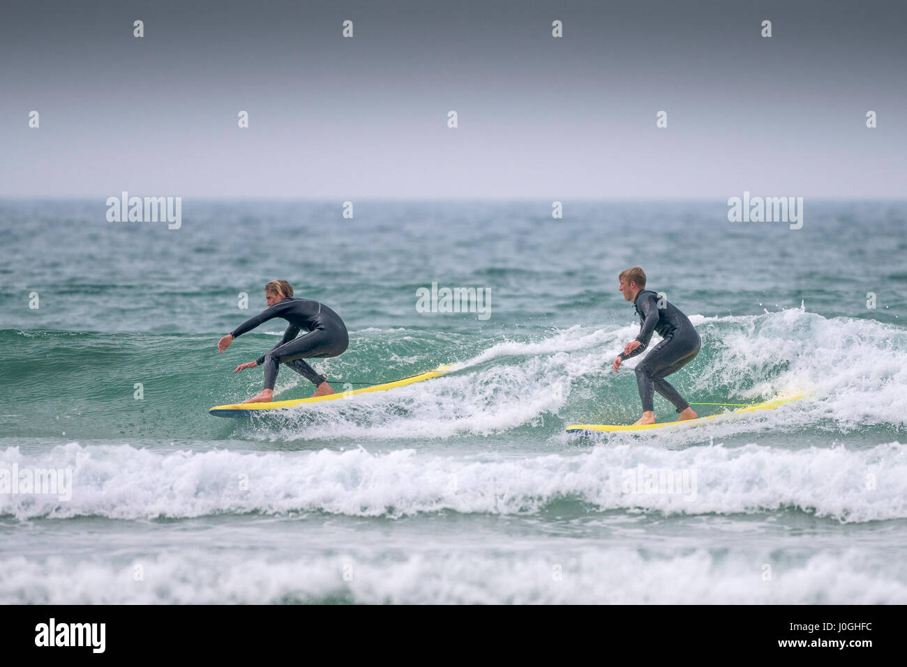 Gwithian Towans Surfer Surfen UK zwei Surfer Skill Balance Balancing Meer kalt Freizeitbeschäftigung Fähigkeit Urlaubsaktivität Stockfoto