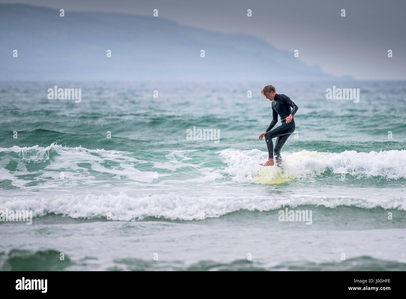 Gwithian Towans beach Surfer Surfen Balance balancieren Meer Skill kalte Küste Küste Urlauber Freizeitbeschäftigung Urlaubsaktivität Stockfoto