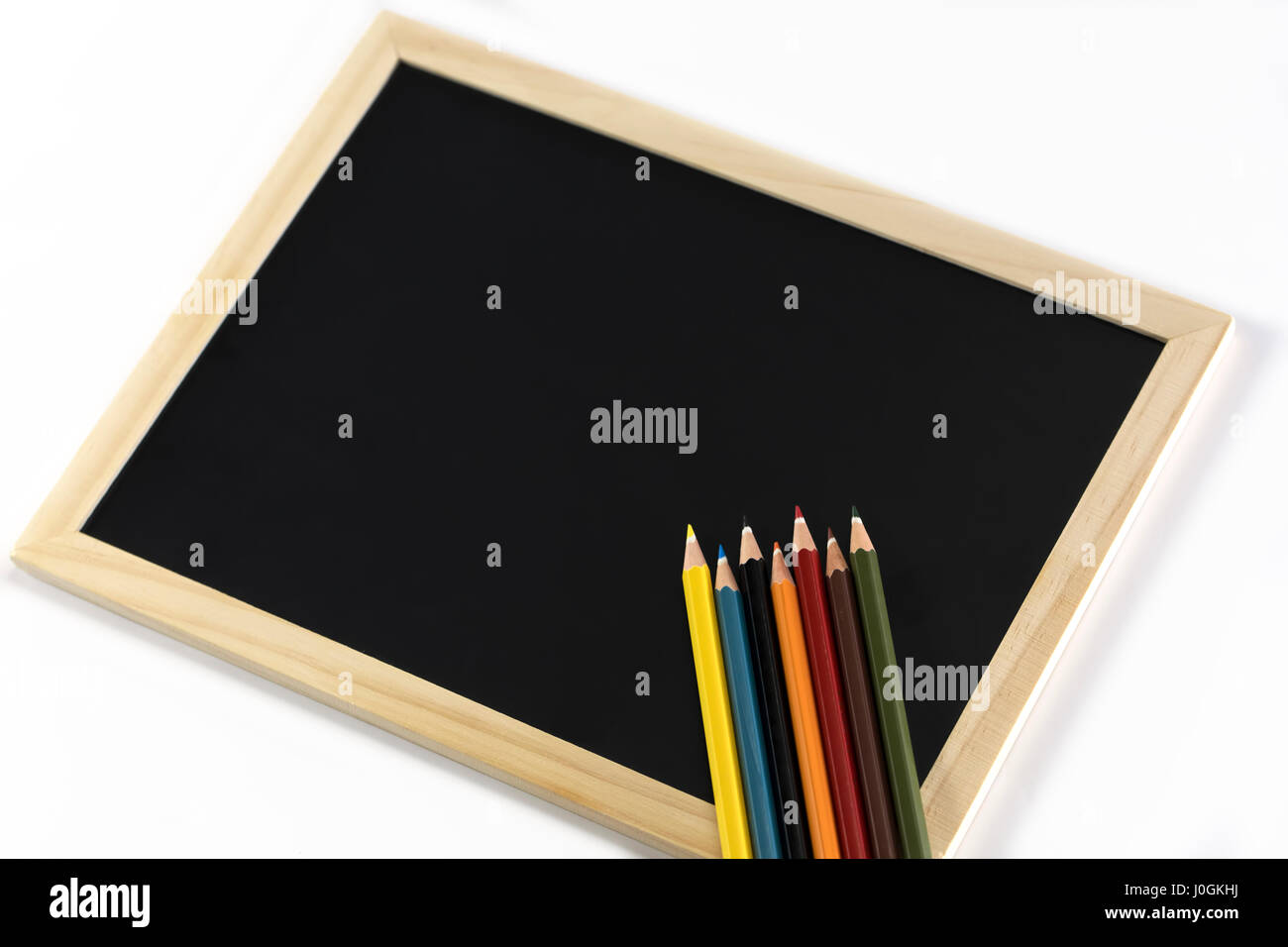 Farbstiften am schwarzen Brett isoliert auf weißem Hintergrund Stockfoto