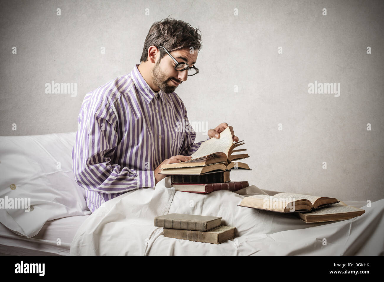 Mann mit Brille lesen von Büchern im Bett Stockfoto