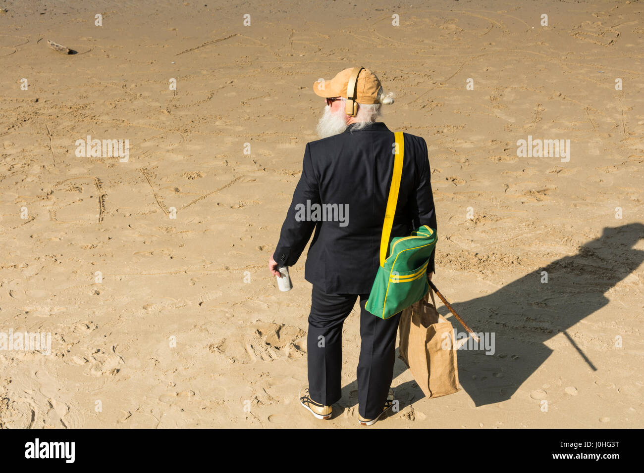 Ein älterer Mann steht am Sandstrand neben dem Fluss Themse in der Nähe von Londons South Bank. Stockfoto