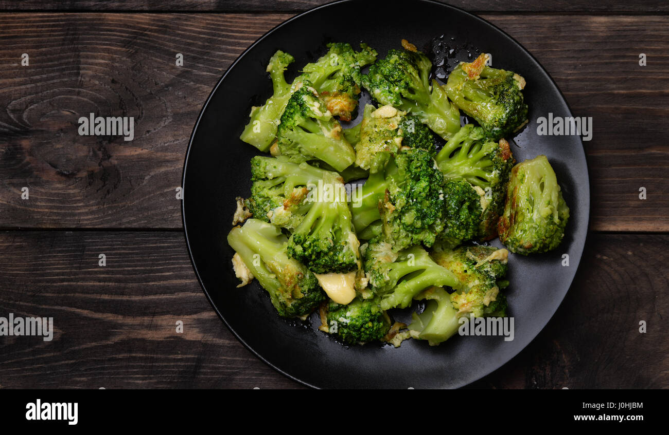 Draufsicht der Platte mit gebratenem Brokkoli auf dunklen Holztisch Stockfoto