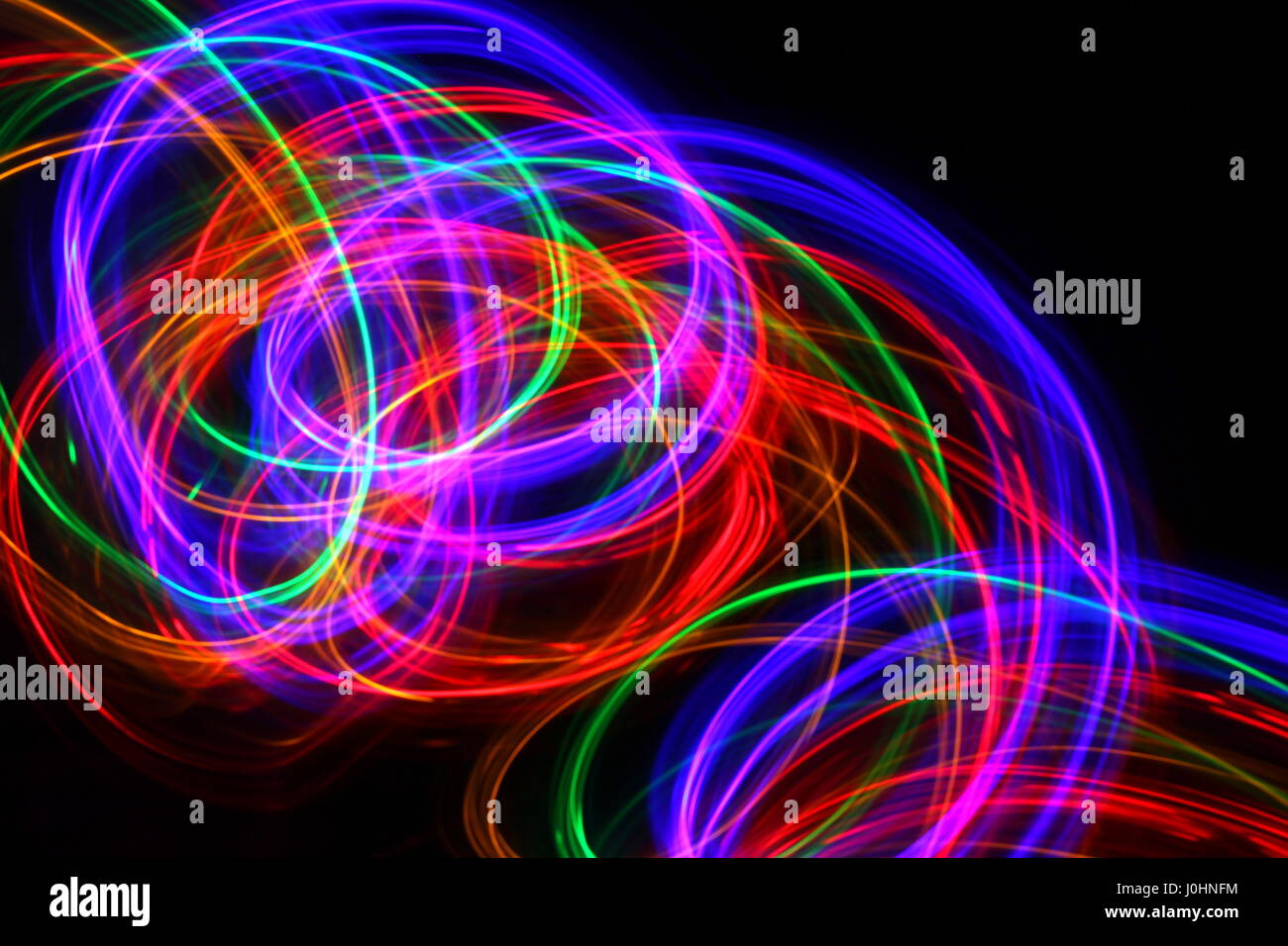 Licht Malerei Foto von mehrfarbigen Lichterketten in einem Strudel Muster vor einem schwarzen Hintergrund. Fotos mit langer Belichtungszeit. Neon Multi Color. Stockfoto