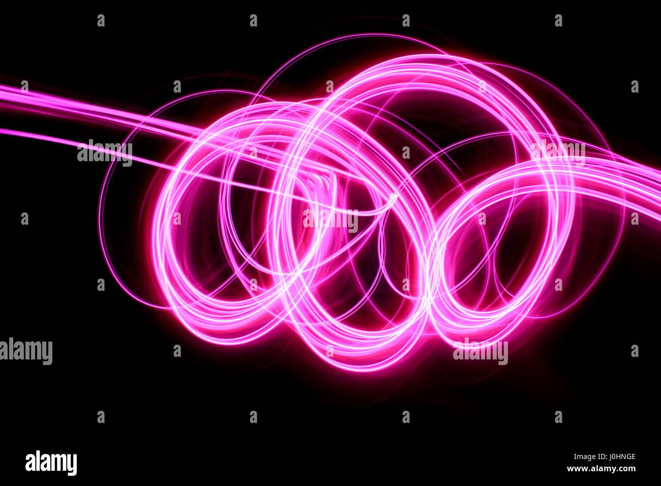 Rosa Licht Malerei Fotografie - lange Belichtung Foto des lebhaften rosa Schleifen und wirbelt auf schwarzem Hintergrund. Abstrakte Licht Muster. Stockfoto