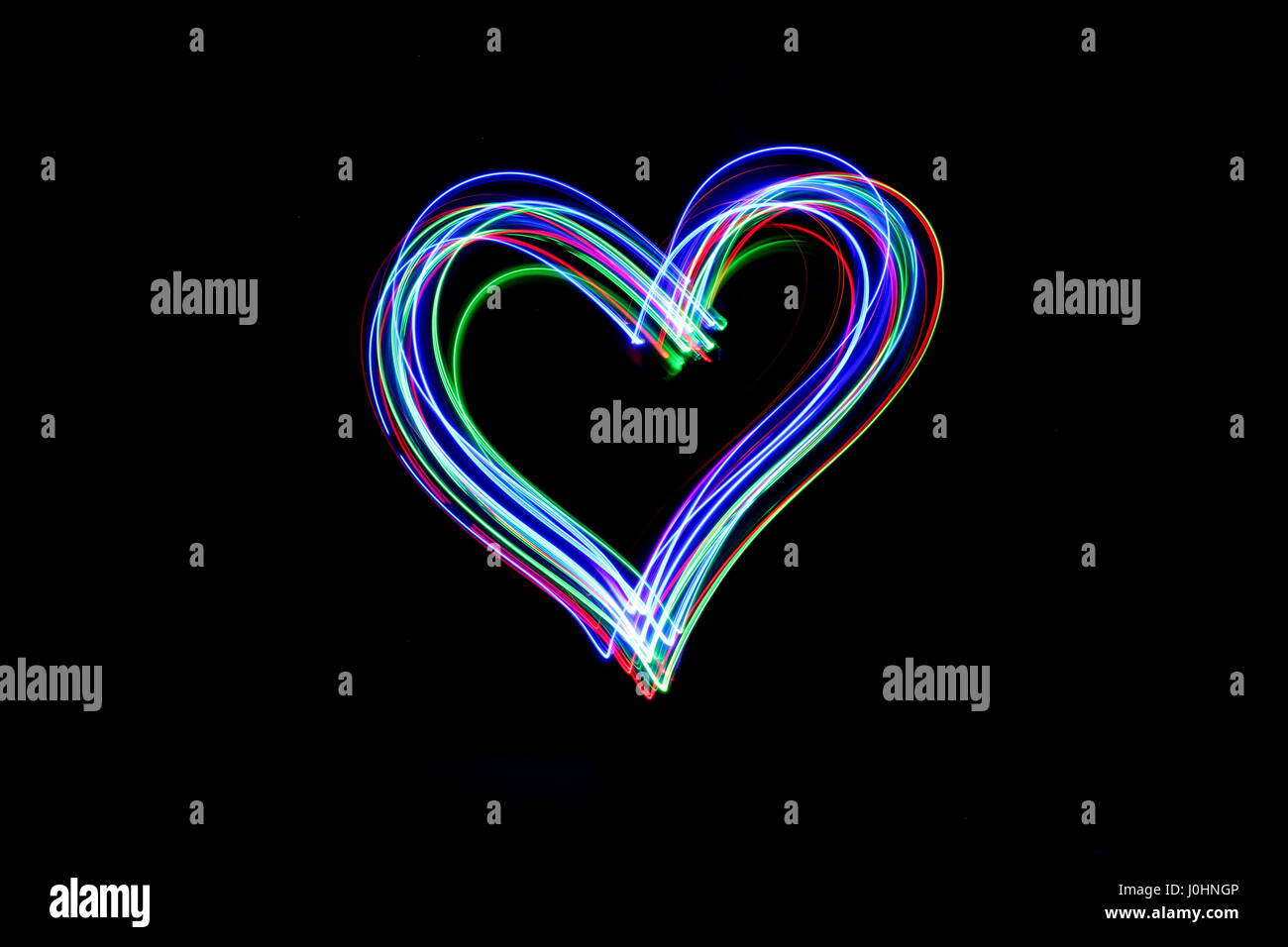 Licht Malerei Fotografie - lange Belichtung Foto von Lichterketten, in Form eines Herzens vor einem schwarzen Hintergrund. Neon abstract das Symbol. Stockfoto