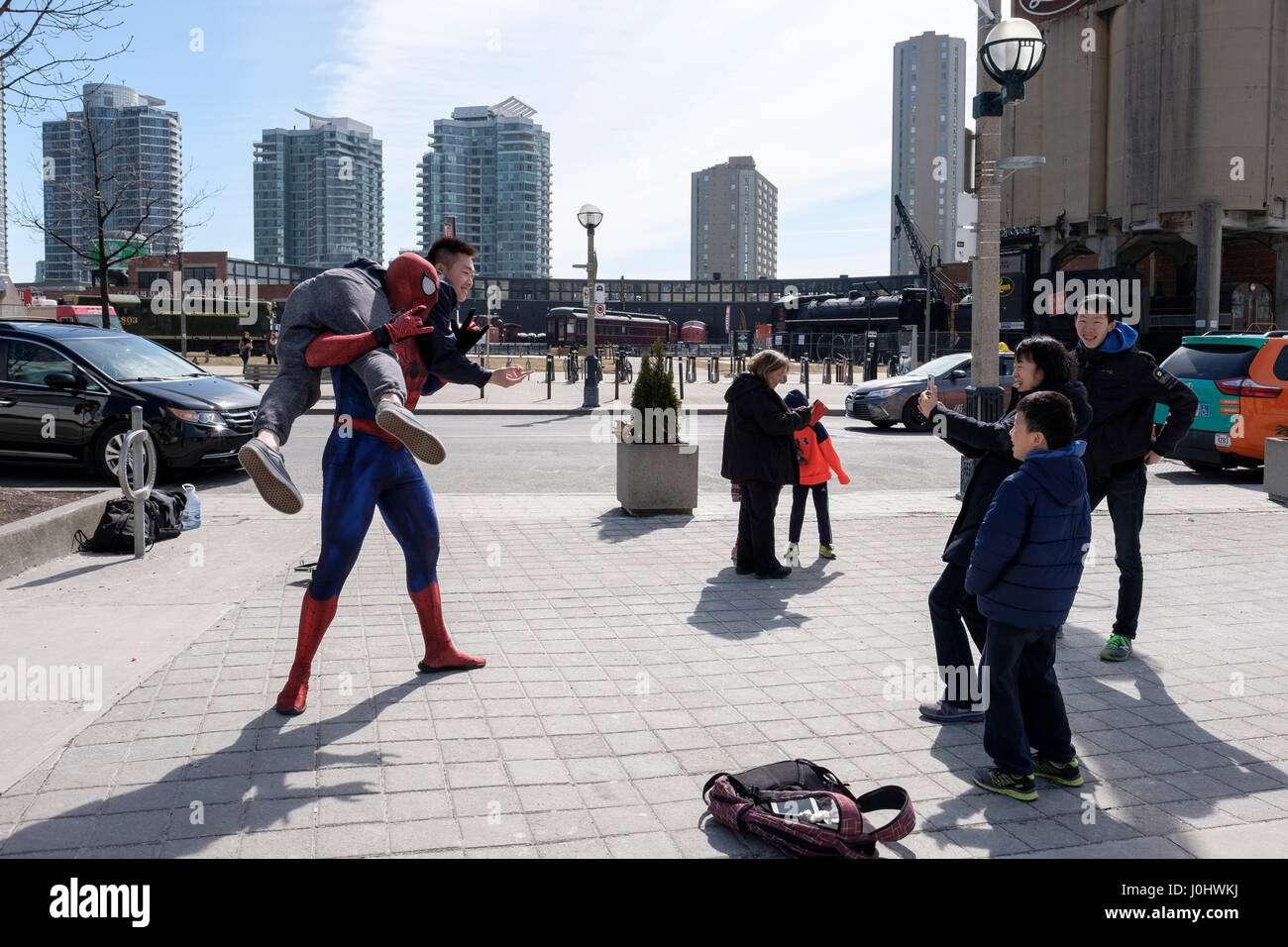 Straßenkünstler, verkleidet als Spider-man, posiert für Touristenfotos, hebt einen asiatischen Touristen vom Boden, Street Life, Toronto, Ontario, Kanada Stockfoto