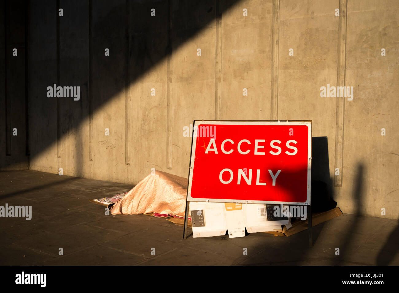 Ein Obdachloser schläft zwischen ein Zugang nur Schild und eine solide Betonwand - Liverpool Street, London April 2017 Stockfoto