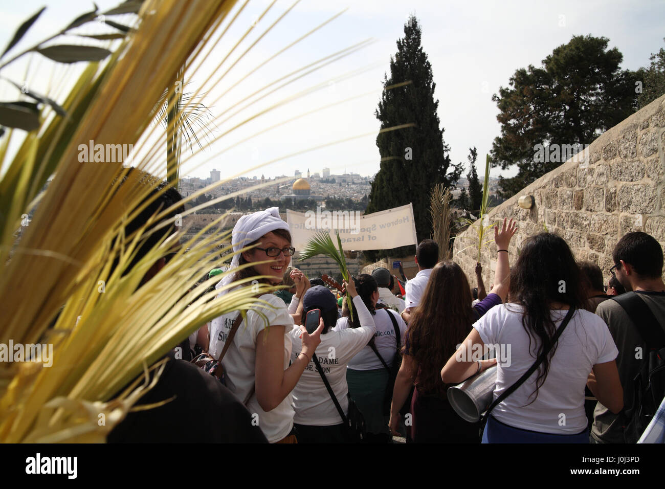 Christlichen Menschen aus aller Welt Spaziergang vom Ölberg in einer Palmsonntag Prozession tragen Palme Niederlassungen, eine Frau dreht. Stockfoto