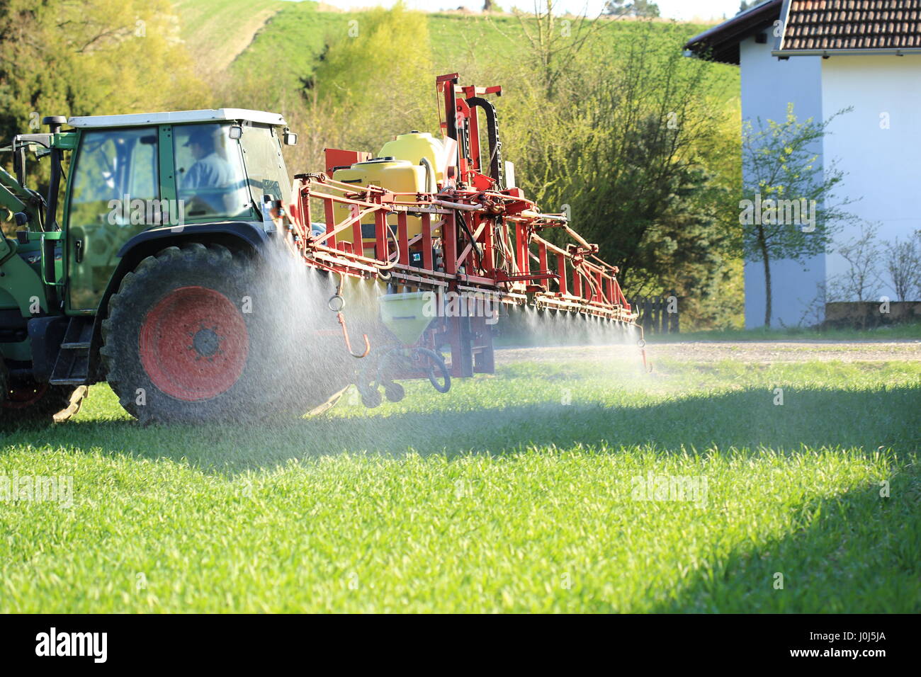 Ein Traktor Sprühen von Pestiziden in der Nähe von Häusern Stockfoto