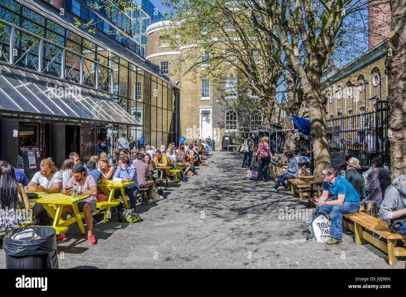 Draußen sitzen Menschen an Trestle Tischen Straße Essen auf der Brick Lane im Osten Londons. Stockfoto