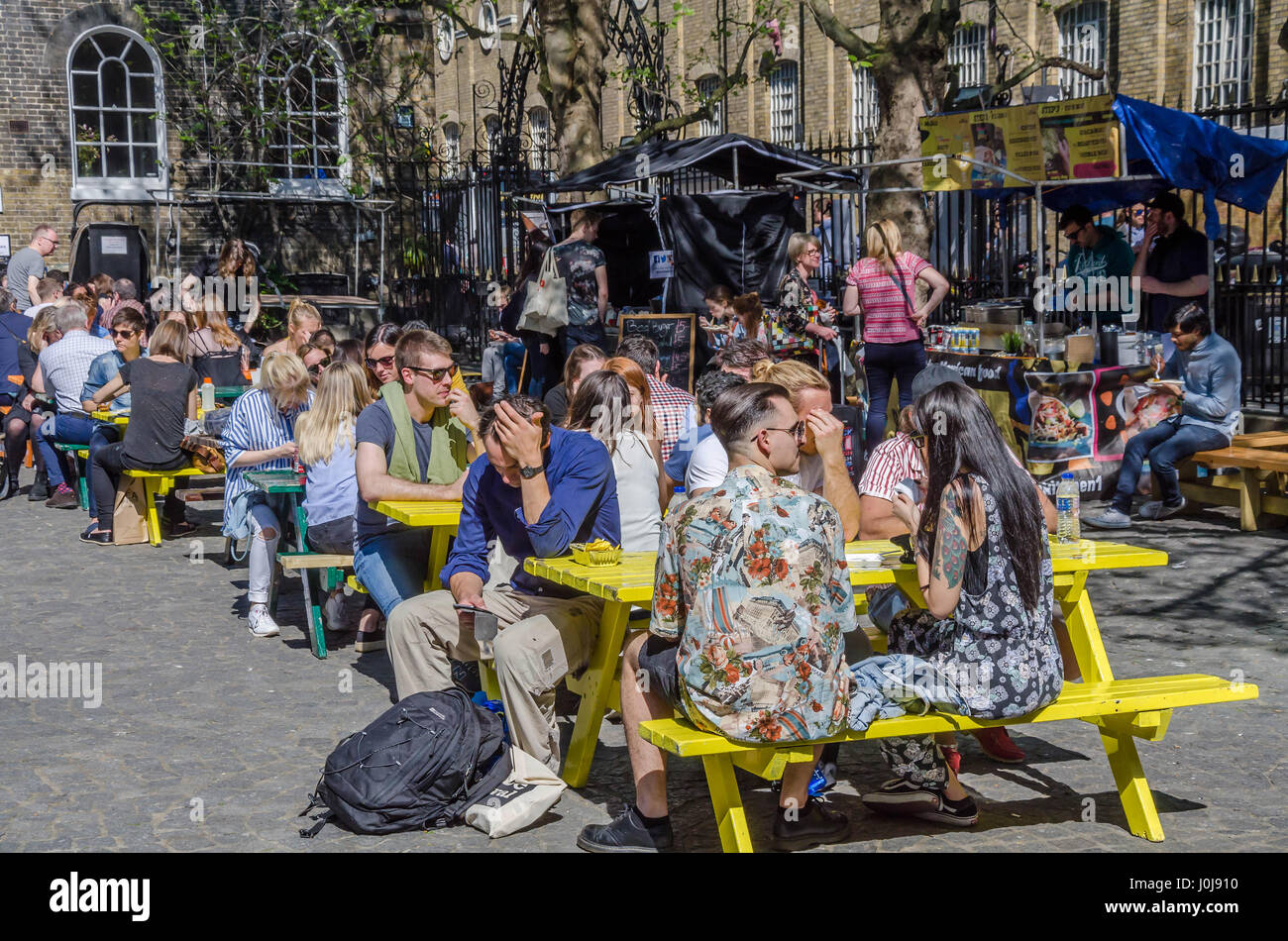 Draußen sitzen Menschen an Trestle Tischen Straße Essen auf der Brick Lane im Osten Londons. Stockfoto