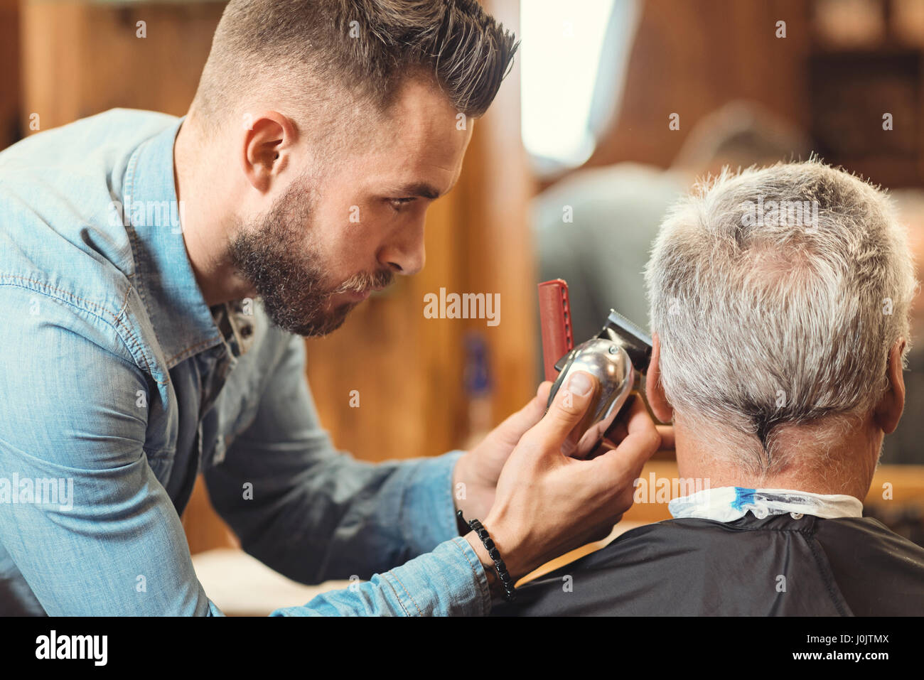 Jungen Barbier Gestaltung Haarschnitt des Alterns Clients im barbershop Stockfoto