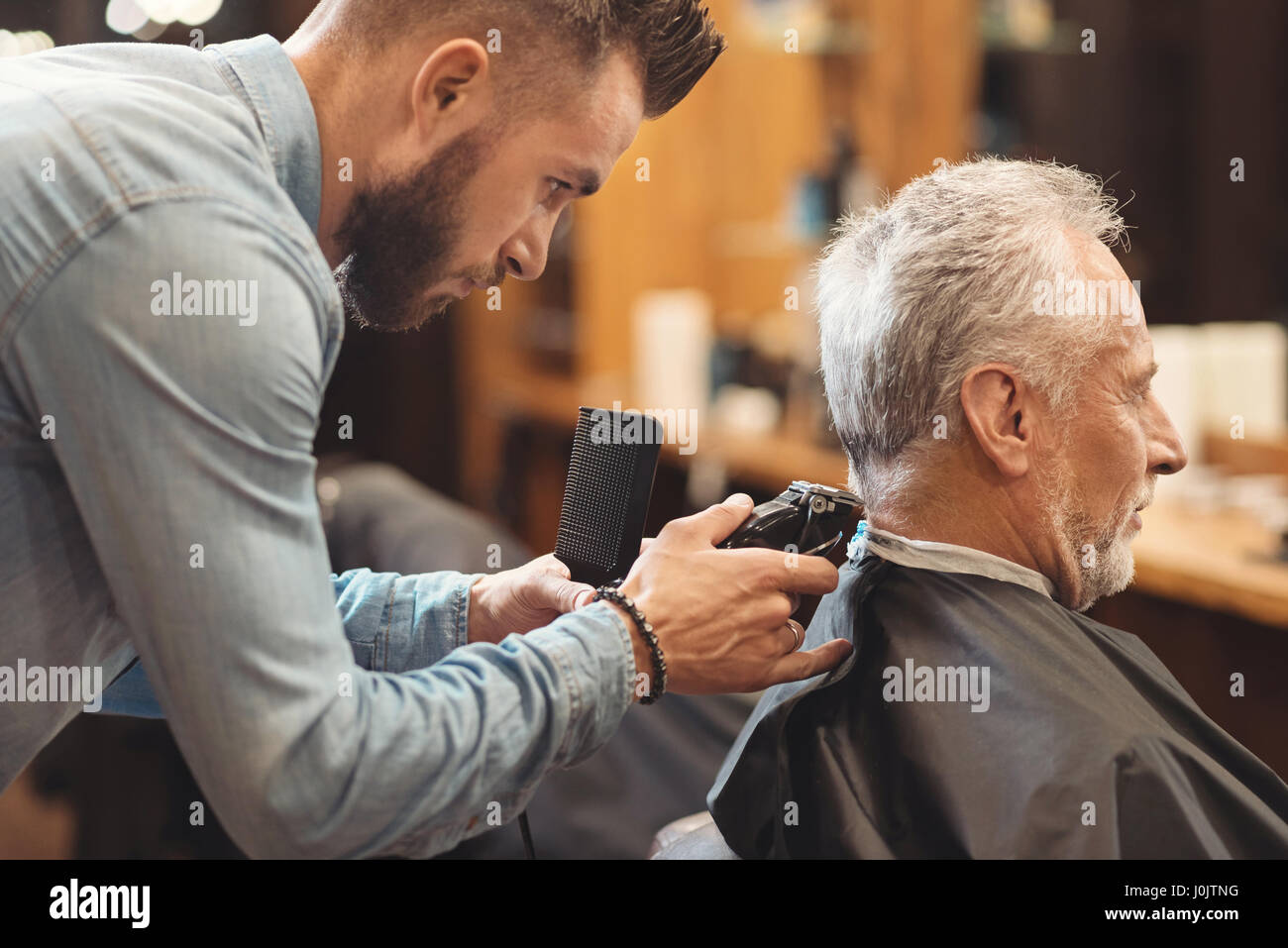Gut aussehend Barbier Gestaltung Haarschnitt des alternden Mannes im barbershop Stockfoto