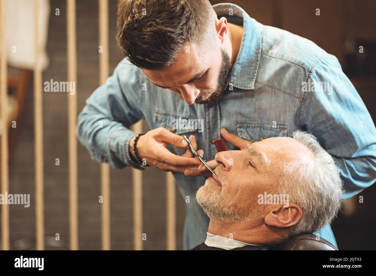 Aufmerksame Friseur Styling Bart des älteren Clients im barbershop Stockfoto