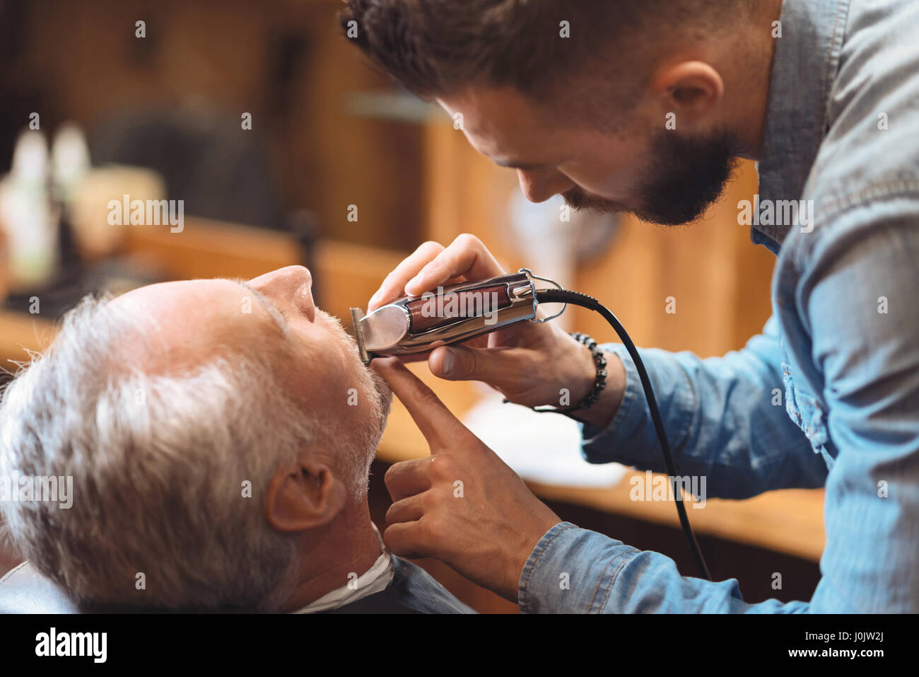 Charismatischen Barbier Gestaltung Bart des Clients im Frisörsalon Stockfoto