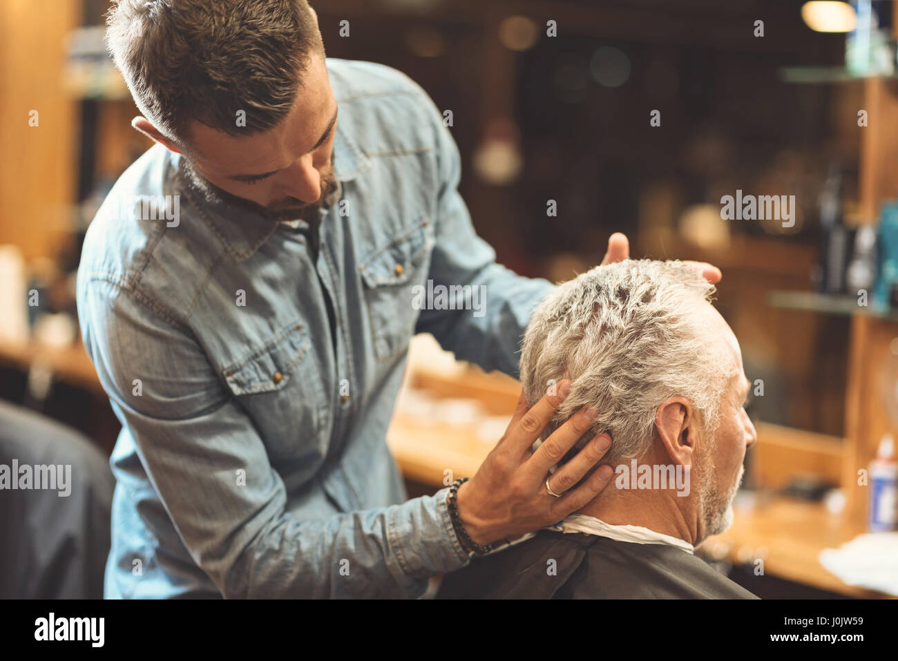 Bärtige Barber, die Gestaltung der Frisur des Kunden im Frisörsalon Stockfoto