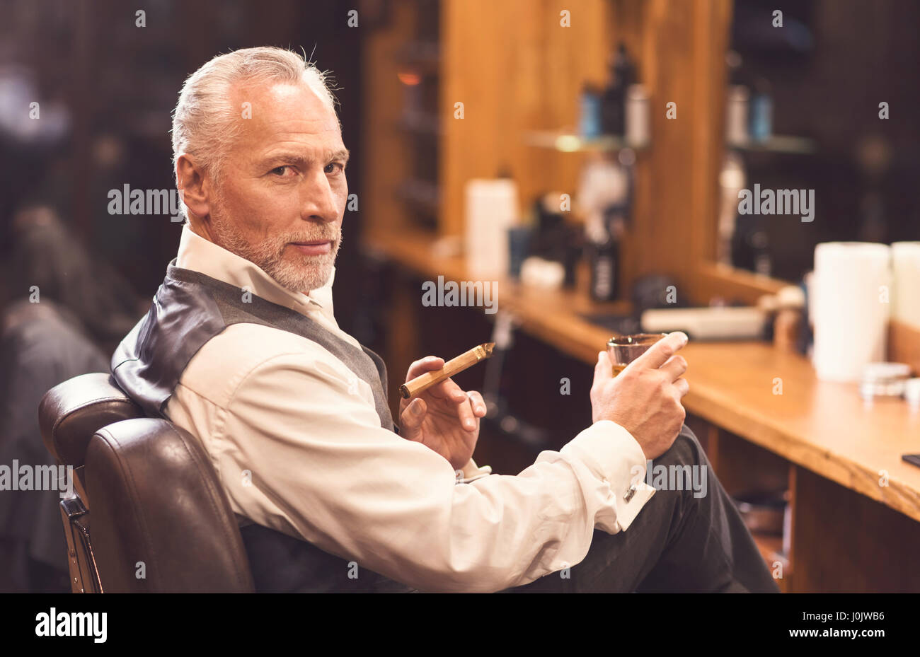 Schöner alter Mann sitzen und genießen die Atmosphäre im Frisörsalon Stockfoto