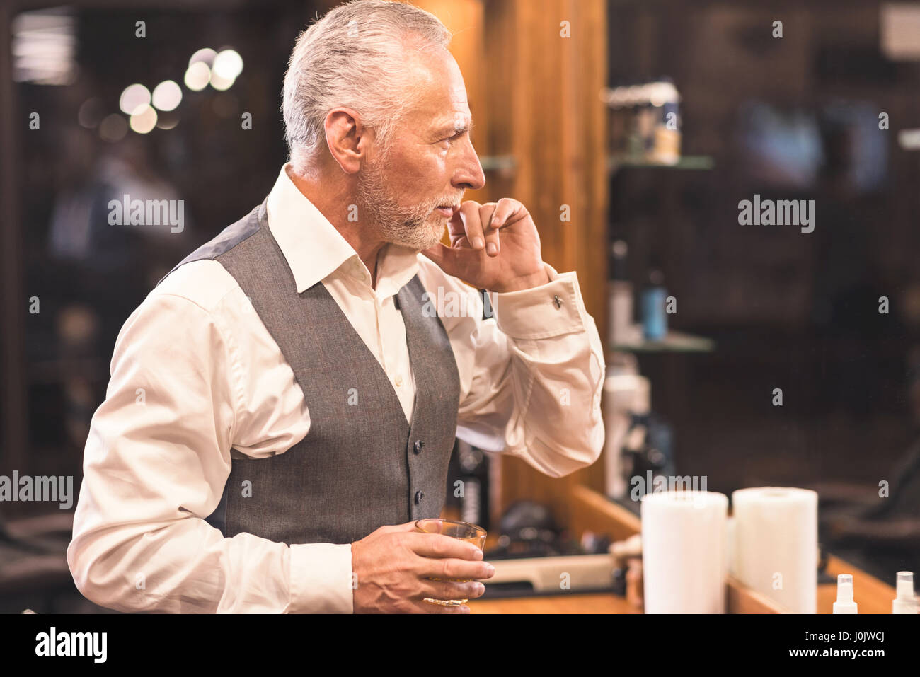 Charismatische Client prüft sein Aussehen nach dem Aufstehen Haarschnitt im barbershop Stockfoto