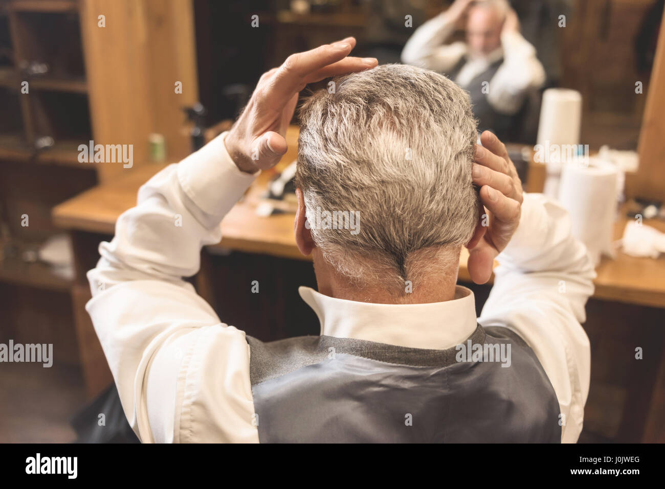 Im Alter von Geschäftsmann seine neue Frisur im Spiegel zu betrachten Stockfoto