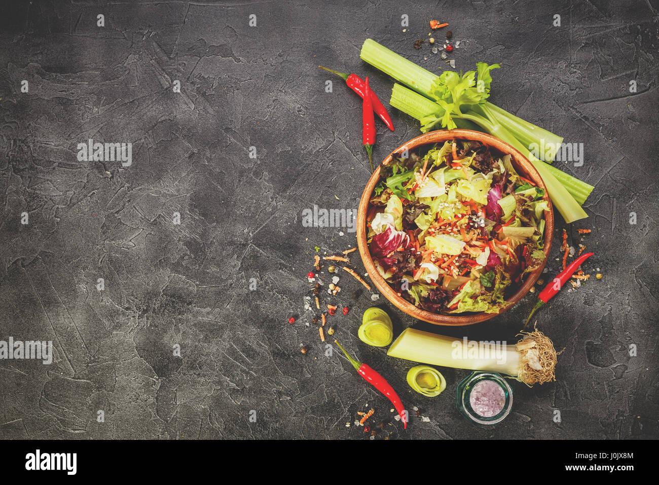 Holzschale mit Salat-Mix Einfrieren, Lollo Rosso, Radicchio, Romano und Iceberg mit Karotten auf schwarzem Hintergrund. Draufsicht mit Platz für text Stockfoto