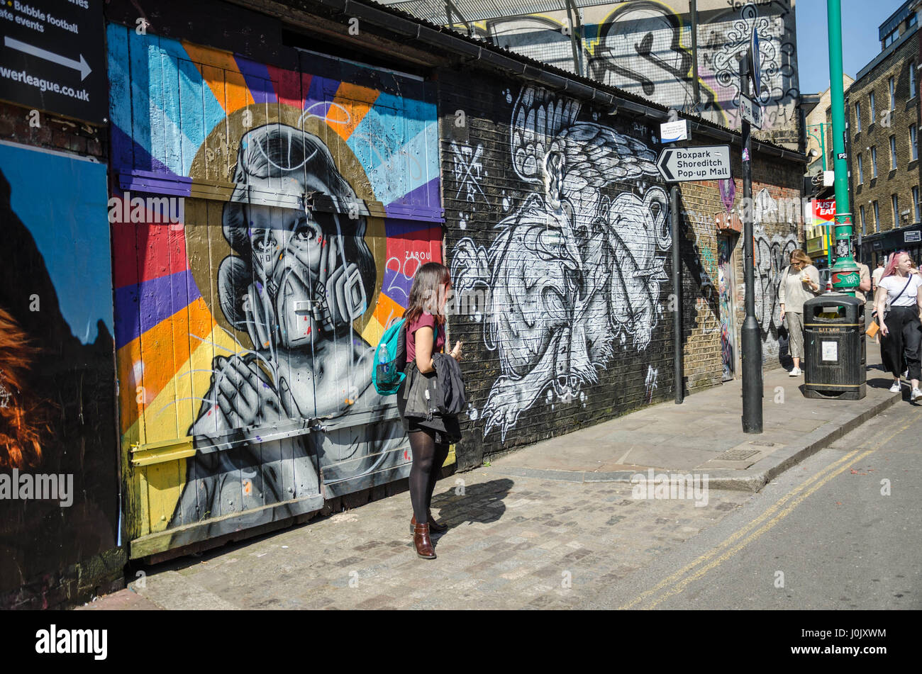 Eine Frau stand vor einer Wand, der fällt in der Straßenkunst auf der Brick Lane im Osten Londons. Stockfoto