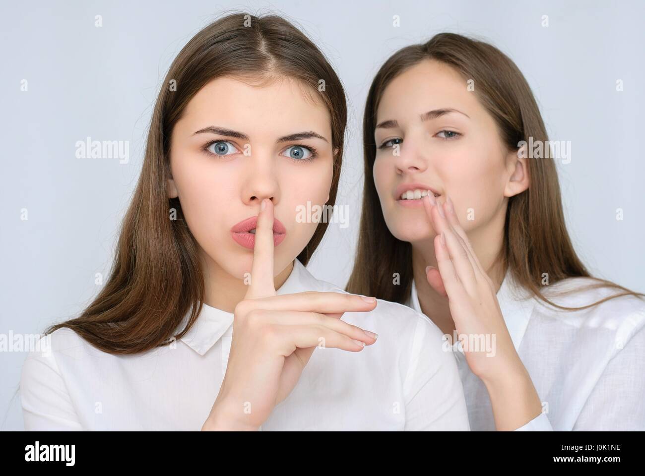 junge Gossip Girl Flüstern an ihre Freundin Ohr Stockfoto