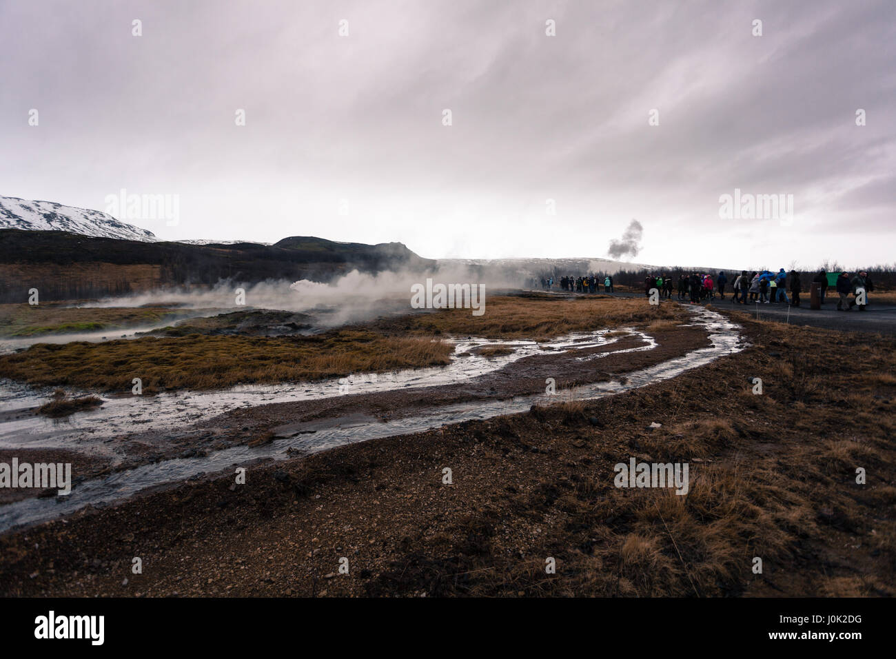 Eine Wolke aus Dampf wabert aus einer geothermischen heißen Quelle als eine Menge von Touristen gehen in Richtung der Geysire. Golden Circle, West-Island Stockfoto