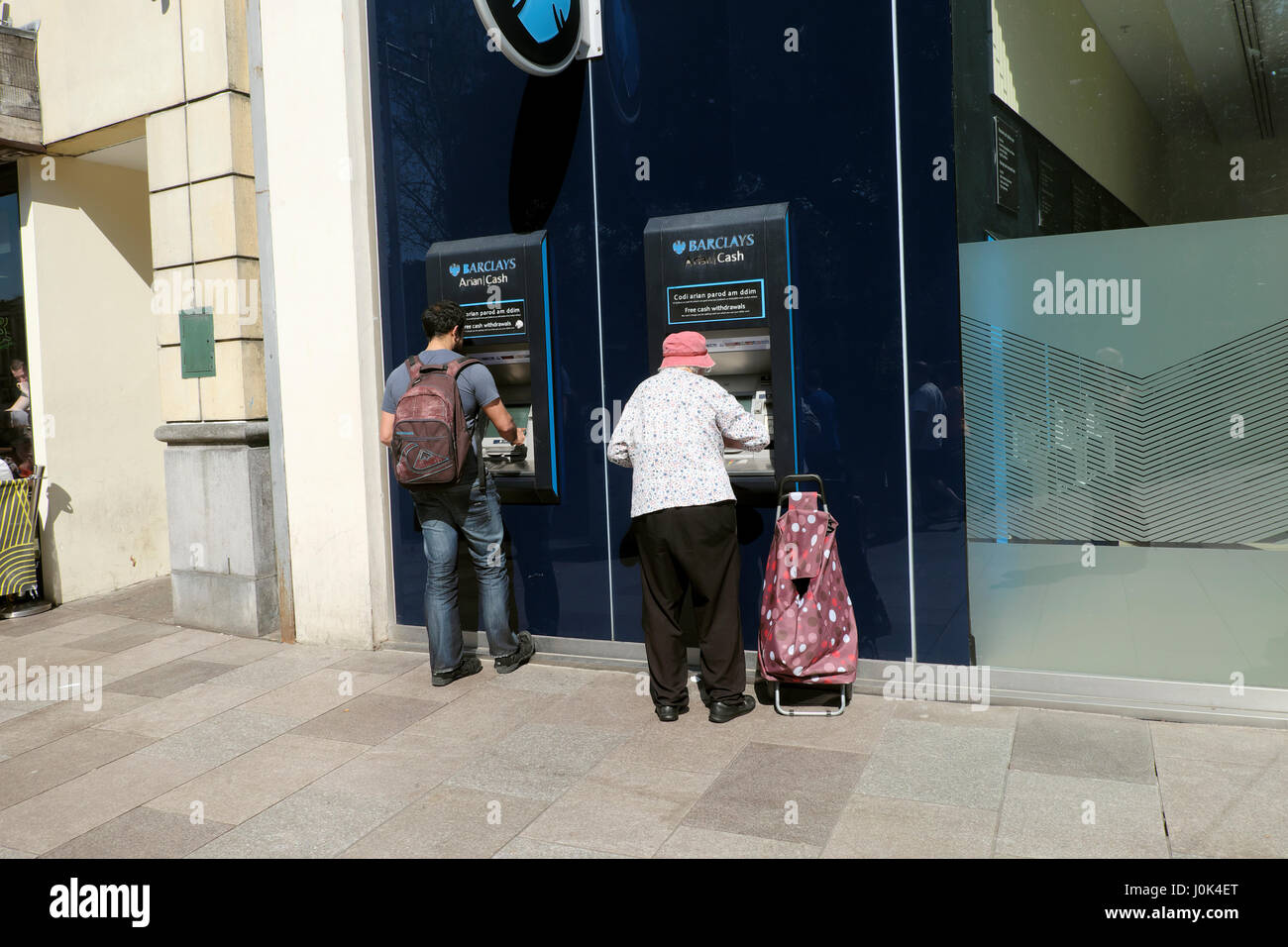 Ältere Frau mit Einkaufswagen immer Geld von Barclays Bank Geldautomaten in der Nähe von Hayes im Stadtzentrum von Cardiff, Wales UK KATHY DEWITT Stockfoto
