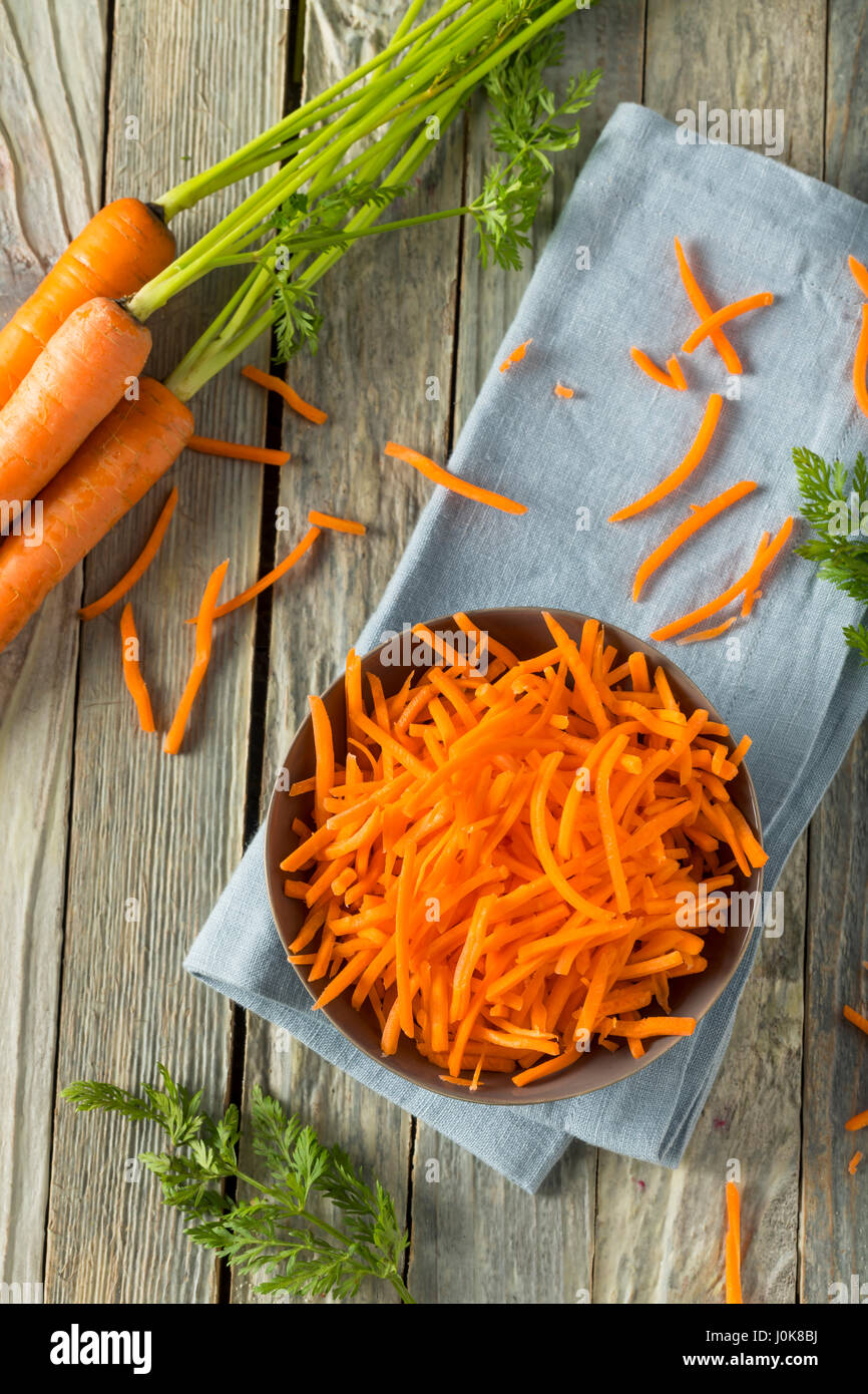 Rohe Bio Orange geriebenen Karotten in eine Schüssel geben Stockfoto