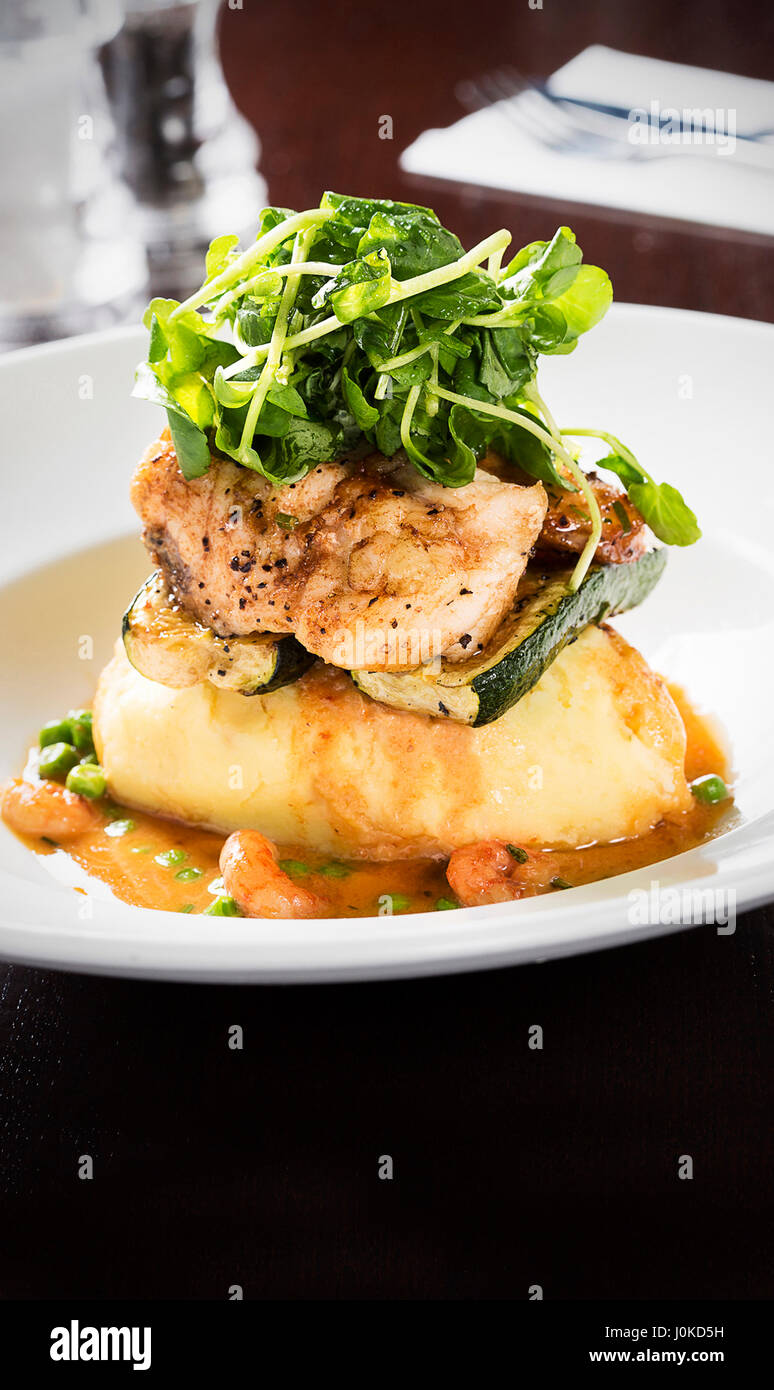 Fisch serviert auf Kartoffelpüree mit Salat Stockfoto