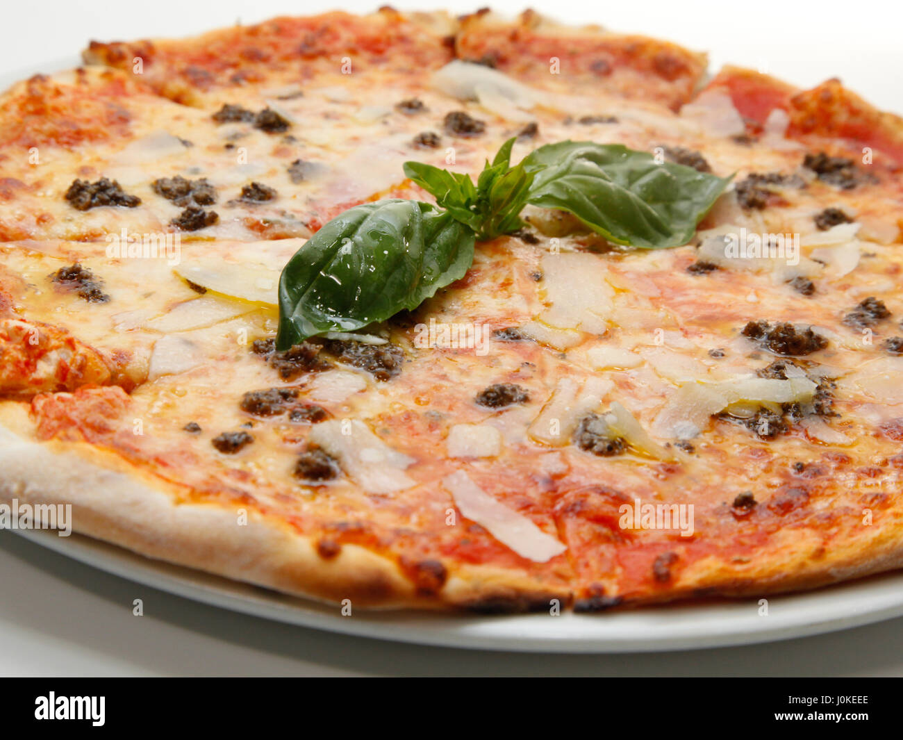 Leckere frische Pizza mit Fleisch, Parmesan und Basilikum auf weißem Hintergrund. Tiefenschärfe, flachen DOF Stockfoto