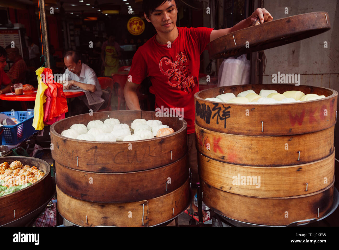 Kuala Lumpur, Malaysia - 17. März 2016: Junger Mann Kochen chinesische traditionelle gedämpfte Brötchen in der Straße Garküche in Chinatown, Kuala Lumpur, Mala Stockfoto