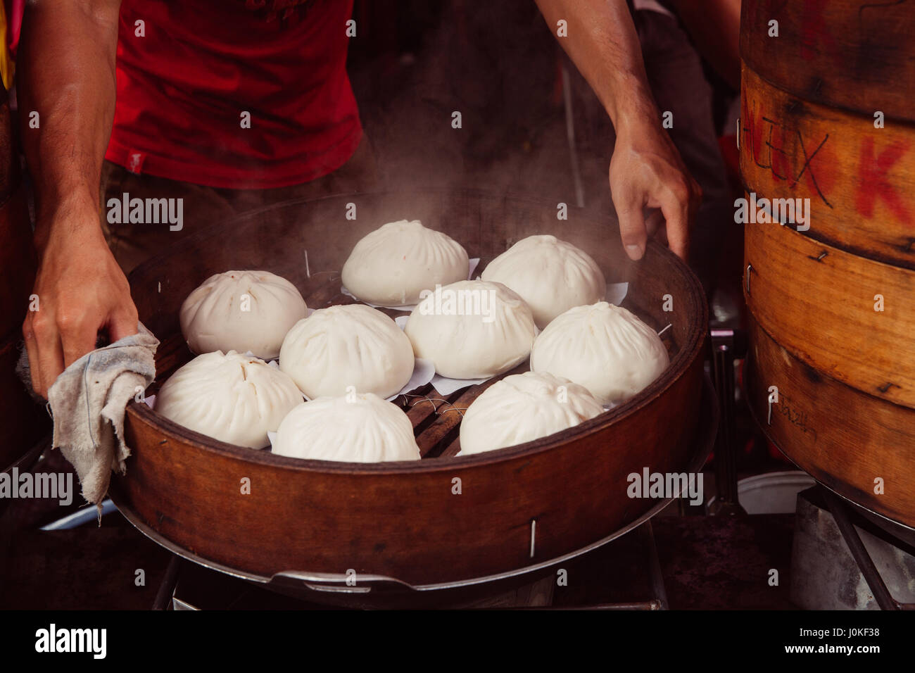 Kuala Lumpur, Malaysia - 17. März 2016: Junger Mann Kochen chinesische traditionelle gedämpfte Brötchen in der Straße Garküche in Chinatown, Kuala Lumpur, Mala Stockfoto