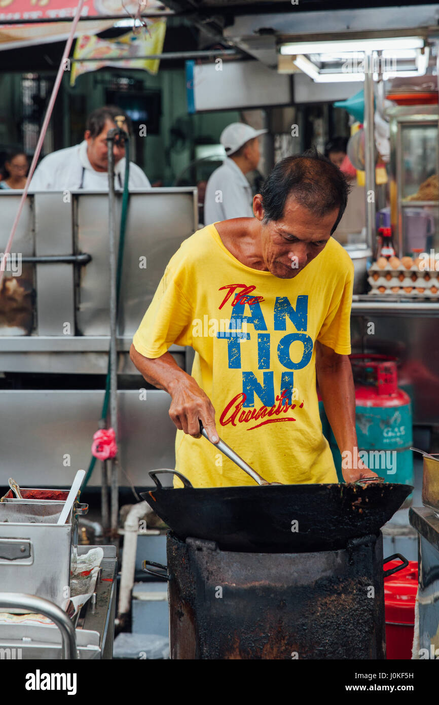 George Town, Malaysia - 22. März 2016: Senior Mann kocht Kway Teow Nudeln im asiatischen Wok auf dem Nachtmarkt Kimberly Street Food am 22. März 2016 in Stockfoto