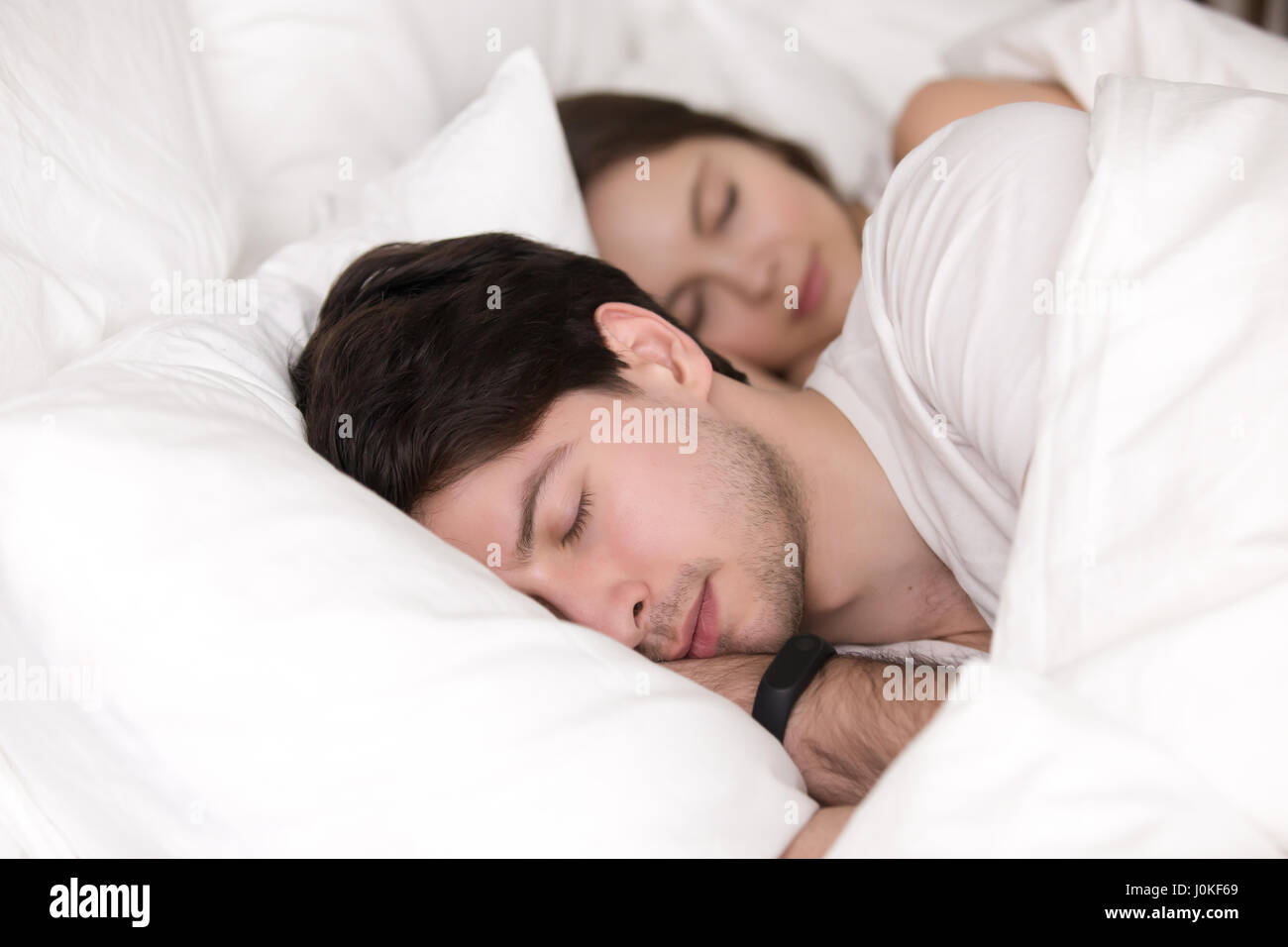 Junges Paar im Bett, Mann mit Smartwatch Tracker schlafen Stockfoto