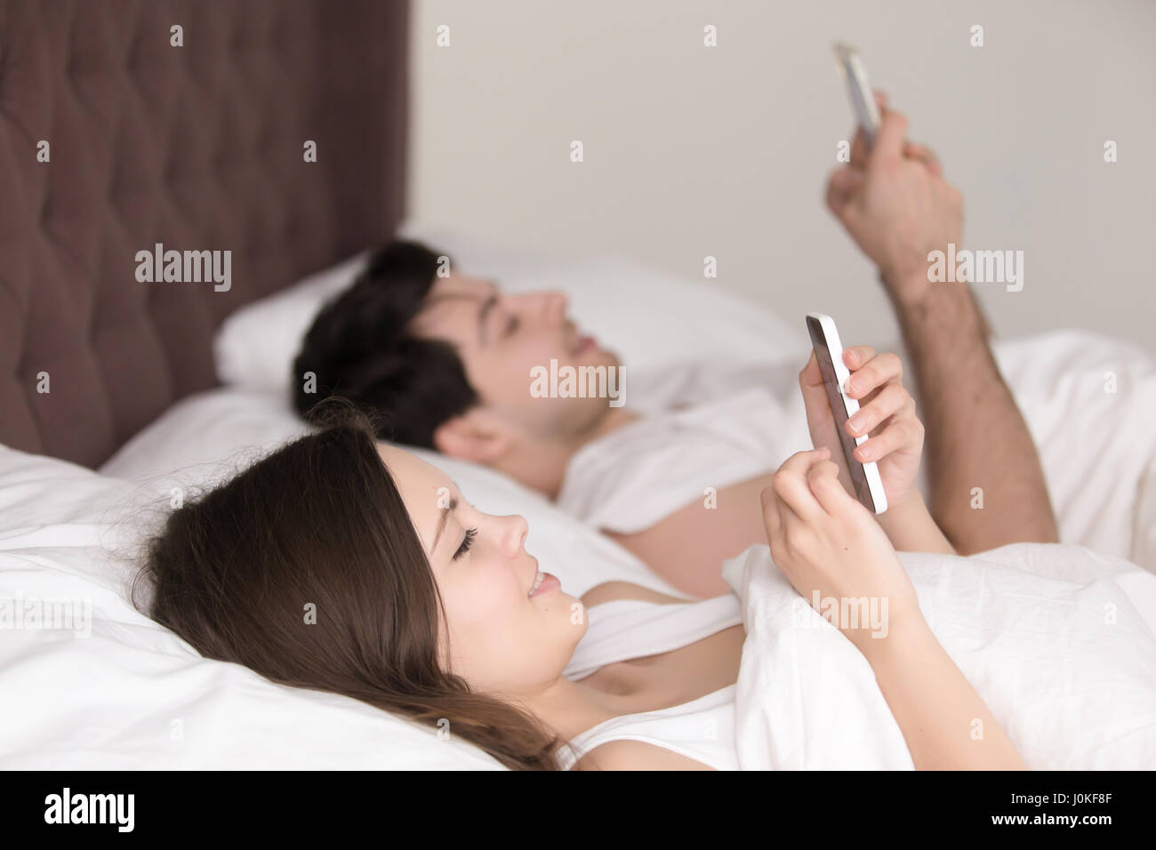 Happy couple jeder mit eigenen Smartphone auf Bett liegend Stockfoto