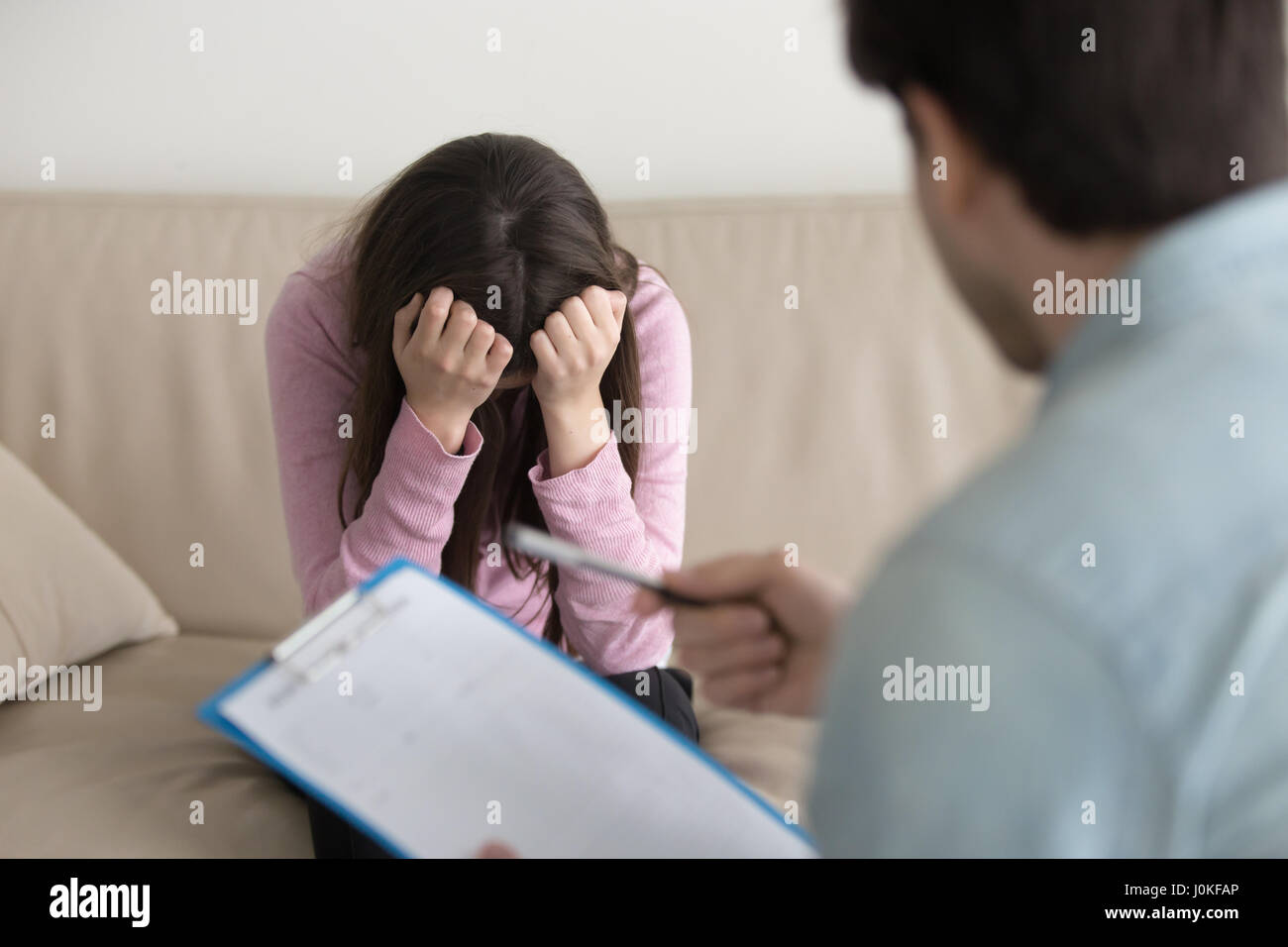 Deprimiert weinende Frau sitzt mit dem Kopf nach unten, Psychologe Stockfoto