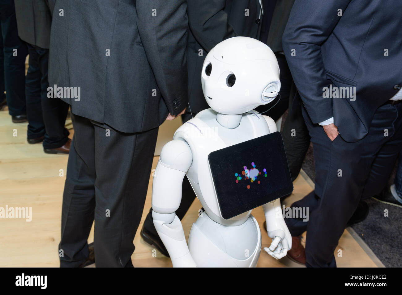 Hannover, Deutschland - 22. März 2017: Der humanoide Roboter Pfeffer von SoftBank Group zwischen Männern in Anzügen auf dem ibm-Stand auf der CeBIT 2017. Stockfoto