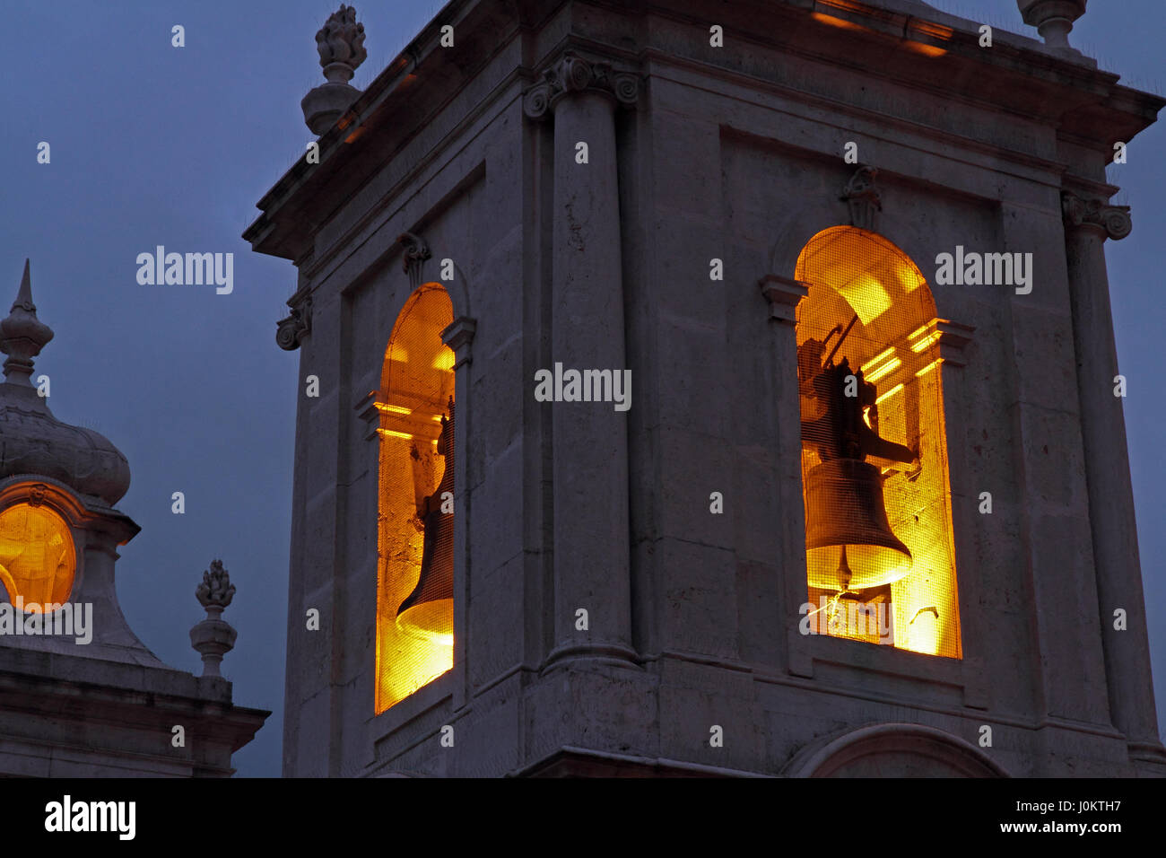 Nahaufnahme von einem Kirchturm in der Nacht mit den Glocken von Lichtern beleuchtet. Stockfoto